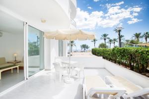 eine Terrasse mit einem Tisch, Stühlen und einem Sonnenschirm in der Unterkunft Apartamentos Morito Beach in Cala Millor