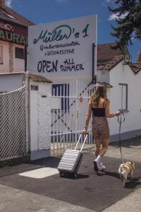 a woman walking a dog and pulling a suitcase at Müller's 1 in Siófok