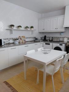 a kitchen with a white table and white cabinets at Casa Branca Pinhal in Nazaré