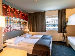 a hotel room with a bed and a painting on the wall at B&B Hotel München City-West in Munich