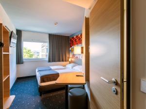 um quarto de hotel com uma cama e uma secretária em B&B Hotel München City-West em Munique