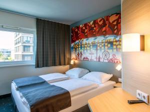 a bedroom with a bed and a painting on the wall at B&B Hotel München City-West in Munich