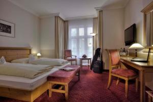 a hotel room with a bed and a desk and chair at Hotel zum ERDINGER Weißbräu in Erding