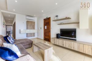 ein Wohnzimmer mit einem Sofa und einem Flachbild-TV in der Unterkunft Spacious, designer 2BR home with Captivating Views by 360 Estates in Mellieħa