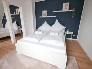 uma cama branca com almofadas brancas num quarto em 110 m2, Dachterrasse, Küche, zentral, ruhige Lage em Paderborn