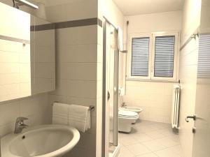 ein weißes Bad mit einem Waschbecken und einem WC in der Unterkunft White Palace Malpensa in Gallarate