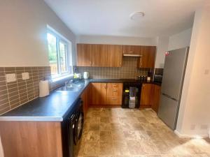 kuchnia z drewnianymi szafkami i lodówką ze stali nierdzewnej w obiekcie Ideal 2 Bedroom Glasgow Home w Glasgow