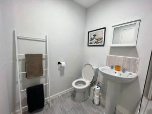 Ideal 2 Bedroom Glasgow Home في غلاسكو: حمام ابيض مع مرحاض ومغسلة