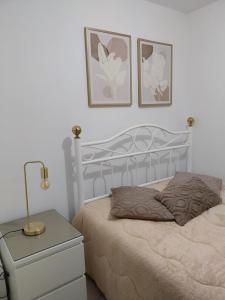 ein Schlafzimmer mit einem Bett, einem Nachttisch und zwei Bildern in der Unterkunft Casa Branca Pinhal in Nazaré
