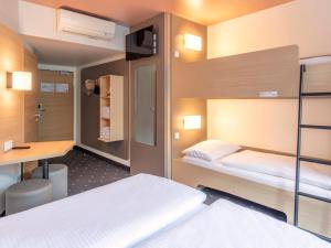 a bedroom with two bunk beds and a desk at B&B Hotel Nürnberg-Hbf in Nuremberg
