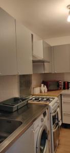 a kitchen with a stove and a washing machine at Richmond London 2 bed room Appartement in London