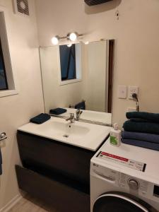 a bathroom with a sink and a mirror and a washing machine at Harbourside Haven in Ohope Beach