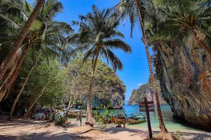 a beach with palm trees and boats in the water at Ko Lanta Amantra Lake View Resort in Ko Lanta