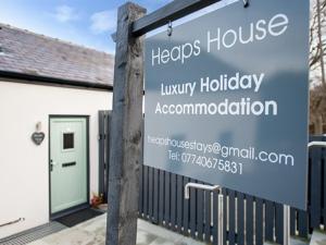 a sign in front of a house with a building at Heaps House in Denby Dale