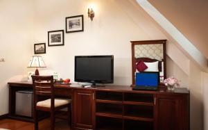 einen Schreibtisch mit einem TV und einem Laptop darauf in der Unterkunft Hanoi Golden Moon Hotel in Hanoi