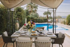 a table set for a meal under a tent next to a pool at Villa Althaea in Loutra