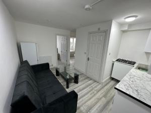 a living room with a black couch and a kitchen at Nice 3 bedroom Bayswater in London