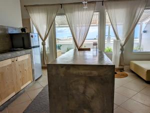 eine Küche mit einer großen Insel in einem Zimmer mit Fenstern in der Unterkunft Tropical Leaves Sea view penthouse in Sal Rei