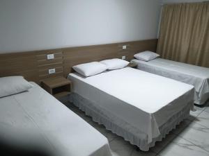 um quarto com três camas num quarto de hotel em Hotel Rio Paraná em Guaíra