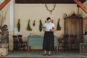 Una donna in piedi in una stanza con un piatto di cibo di Tourist Farm Pr'Dovar a Cerklje na Gorenjskem