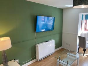 Coastal Apartment 2 Bedrooms, Sleeps upto 6, Free Parking في Prestonpans: غرفة معيشة مع تلفزيون على جدار أخضر