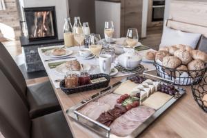 Aadla Walser-Chalets mit privater Sauna, Hotpot und Hotelservice في شروكين: طاولة مليئة بالطعام وكؤوس من النبيذ