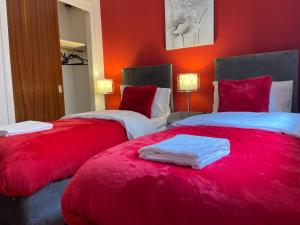 2 camas en una habitación con paredes rojas en Coastal Apartment 2 Bedrooms, Sleeps upto 6, Free Parking, en Prestonpans