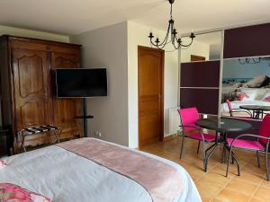 a bedroom with a bed and a table with pink chairs at Ô Mélèze in Morsang-sur-Orge