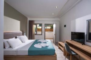 a hotel room with a bed and a flat screen tv at Thania Seaside Smotel - Adults Only in Agia Pelagia