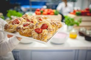 a person holding a tray of pastries with strawberries at Flatbook - City Center SPA Apartments Toruńska 11 in Gdańsk