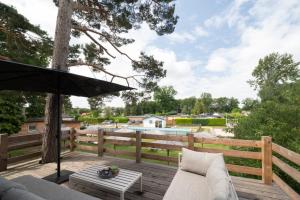 een patio met een parasol, een bank en een tafel bij Recreatiepark Maas en Bos in Wellerlooi