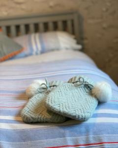 a pair of knitted mitts sitting on a bed at The Sail Loft in Kingsbridge