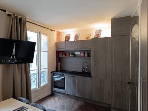 d'une cuisine avec des placards en bois, une cuisinière et une fenêtre. dans l'établissement Studio Pompidou - rue des Temples 3 places, à Paris