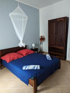 a bedroom with a bed with blue sheets and red pillows at African Sunset in Sal Rei