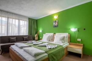 een groene slaapkamer met een bed en een bank bij Grami Hotel in Bansko