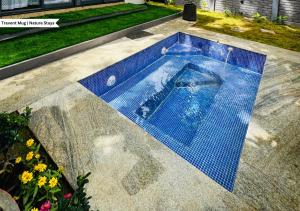 a swimming pool with a blue tile floor and flowers at Oh - Bali Villa by Travent Mug in Rāmanagaram