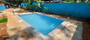 uma piscina num quintal ao lado de uma cerca azul em Stefleena's Nest em Loutolim
