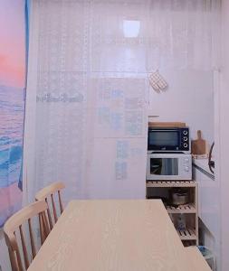une petite cuisine avec une table et un four micro-ondes dans l'établissement Merry Greentea #year-end home party renewal #Jeju island mood #Cozy home #Photo spot, 