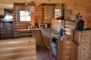 - une cuisine dans une cabane en rondins avec cuisinière et réfrigérateur dans l'établissement LE MARLOTTE, à Sapois