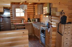 a kitchen in a log cabin with a stove and refrigerator at LE MARLOTTE in Sapois