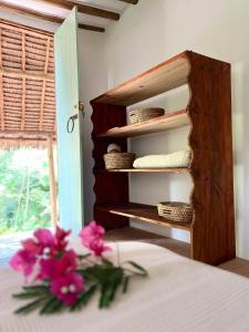 a room with a shelf with pink flowers on a bed at Mawingu lodge in Kizimkazi