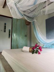 - une chambre avec un lit orné de fleurs roses dans l'établissement Mawingu lodge, à Kizimkazi