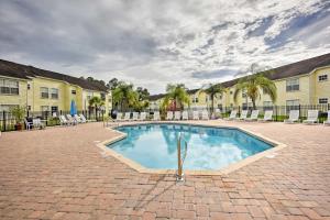 Una piscina en un patio con sillas y un edificio. en Kissimmee Condo with Perks 6 Mi to Disney World!, en Kissimmee