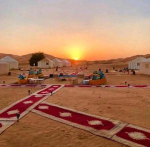 a view of a desert with the sunset in the background at Merzouga luxurious Camp in Merzouga