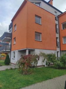 un bâtiment orange et blanc avec une cour verte dans l'établissement Rose Apartament, à Brwinów