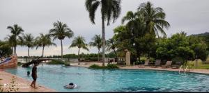 un grupo de personas en una piscina con palmeras en Villa Dalam Laut 580 en Pantai Cenang