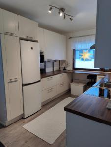 La cuisine est équipée de placards blancs et d'un réfrigérateur blanc. dans l'établissement Laplands Hillside House, à Rovaniemi