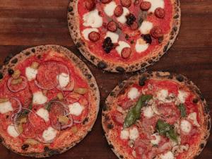 tres pizzas sentadas sobre una mesa de madera en The Stump, en Cirencester