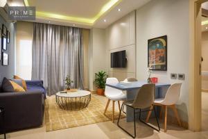 Prime Residence New Cairo في القاهرة: غرفة معيشة مع أريكة وطاولة وكراسي