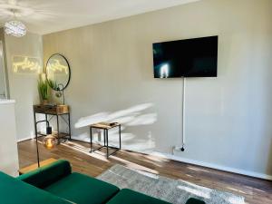 a living room with a green couch and a flat screen tv at Charming Studio Apartment with Free Parking & WiFi in Milton Keynes by HP Accommodation in Milton Keynes